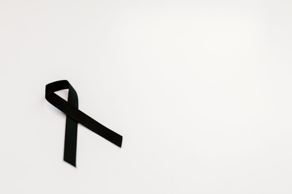 Black ribbon on white. background symbolizing May being skin cancer awareness month.