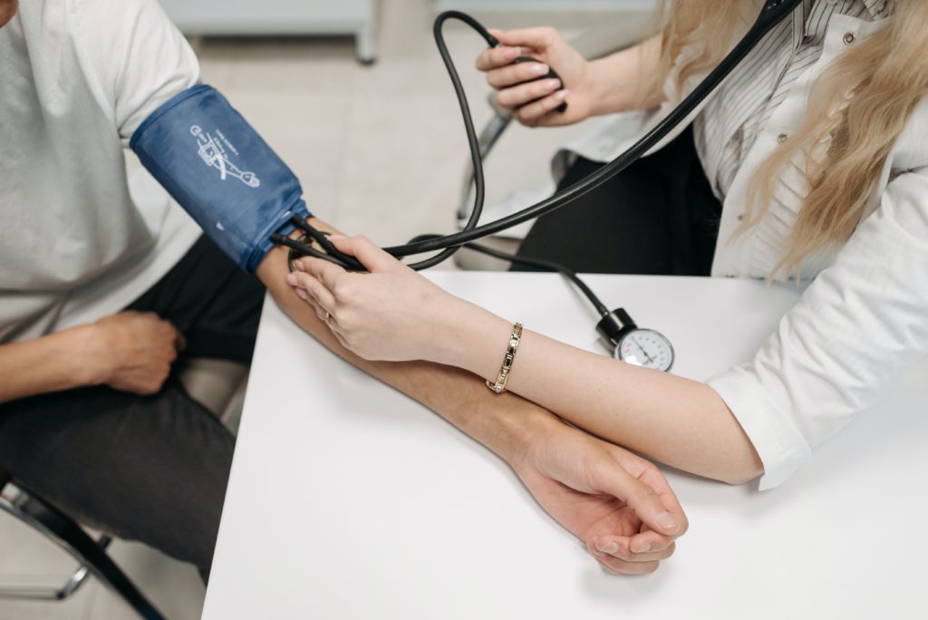 Female Doctor using a blood pressure cuff, or sphygmomanometer, to measure a man's blood pressure.