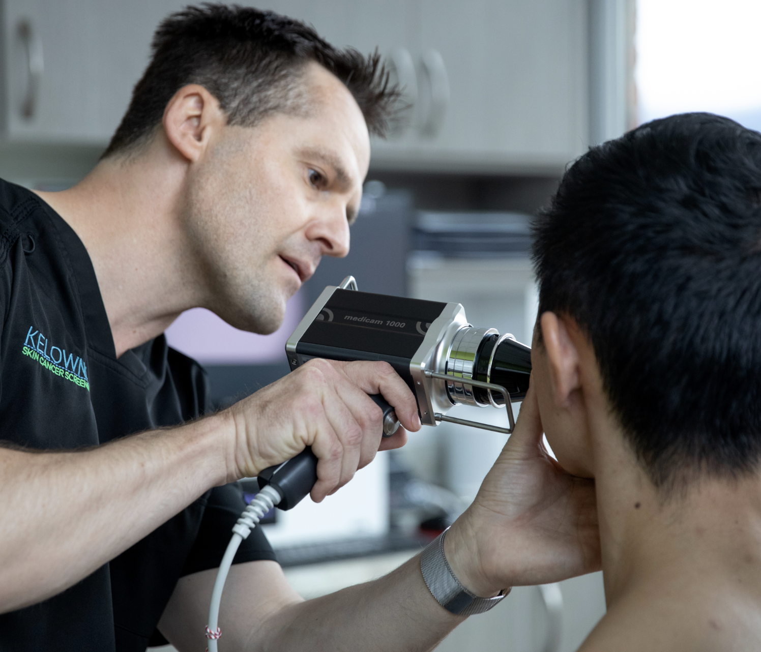 Dr Ben Wiese in his private skin cancer clinic in Kelowna, BC, using a democope on a patient to screen suspicious lesions