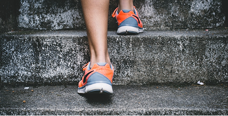 A runner's feet on outdoor stone steps.