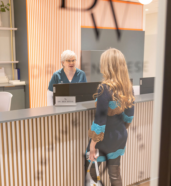 A visitor speaking with staff at the clinic reception desk.