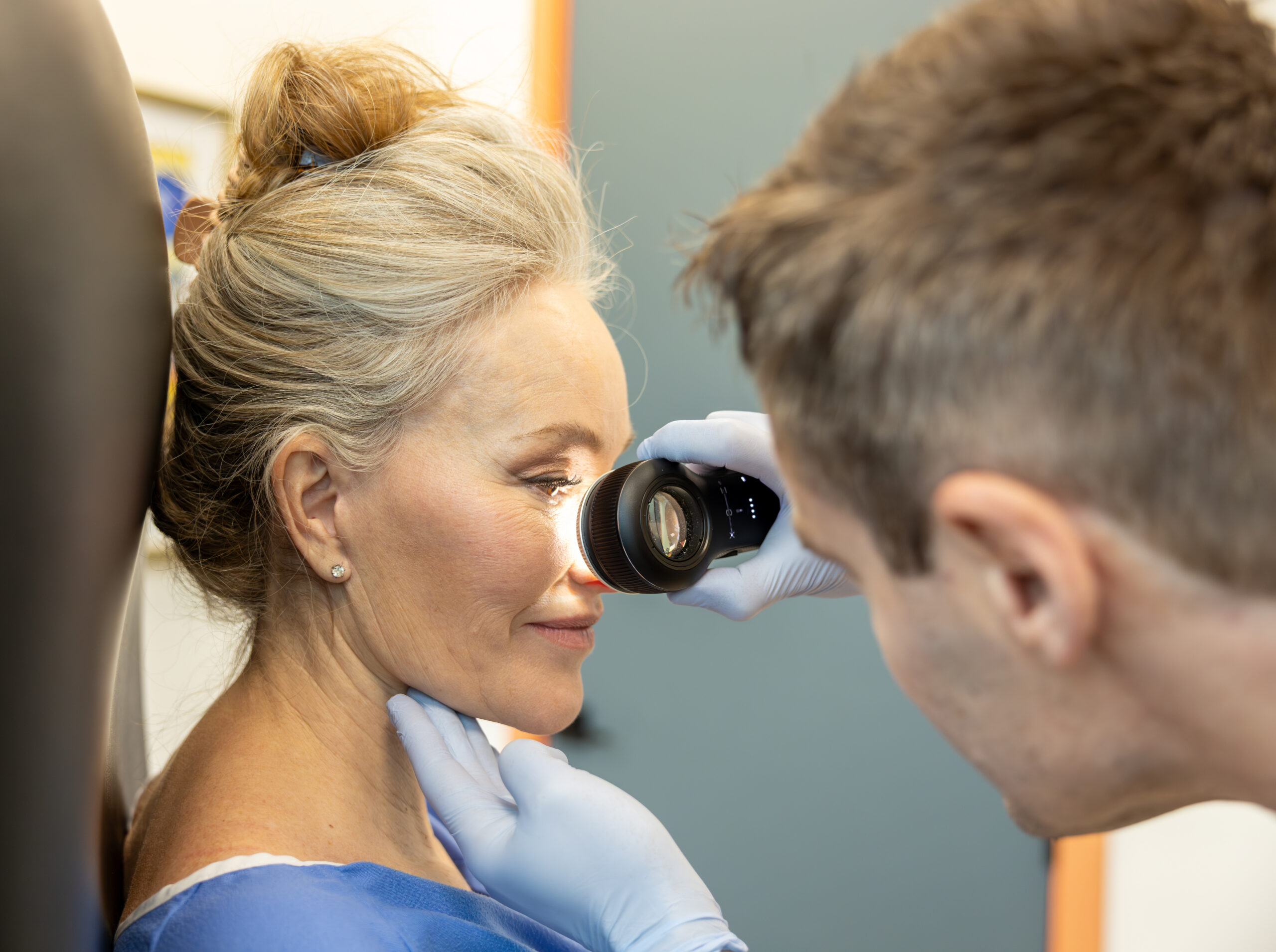 A clinician examining skin with a dermatoscope.