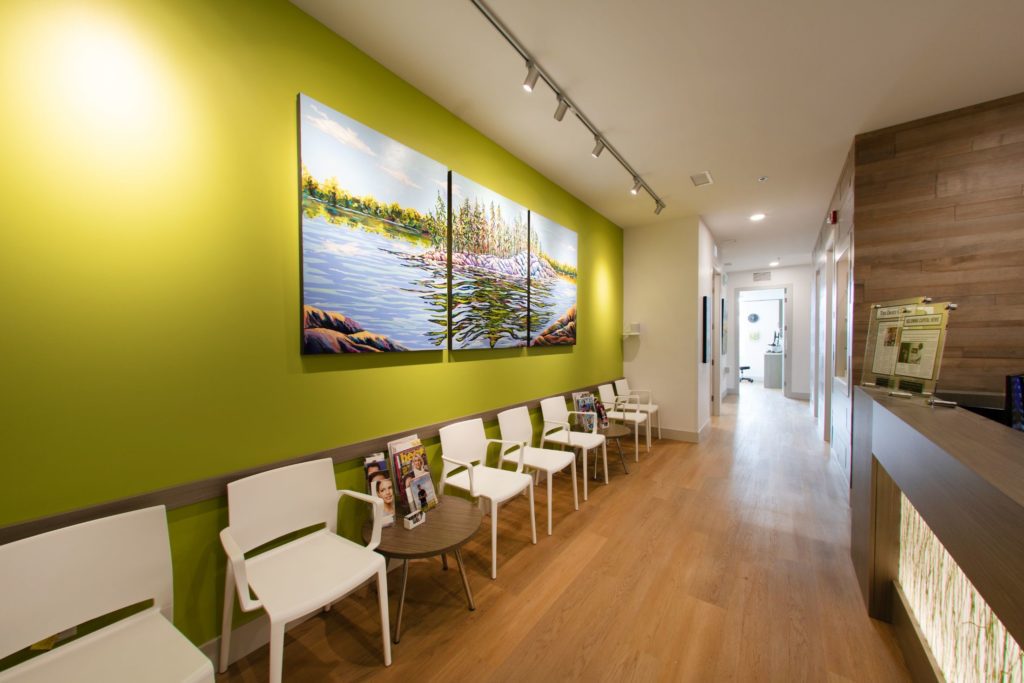 Kelowna Skin Cancer Clinic waiting area with green walls and white chairs.