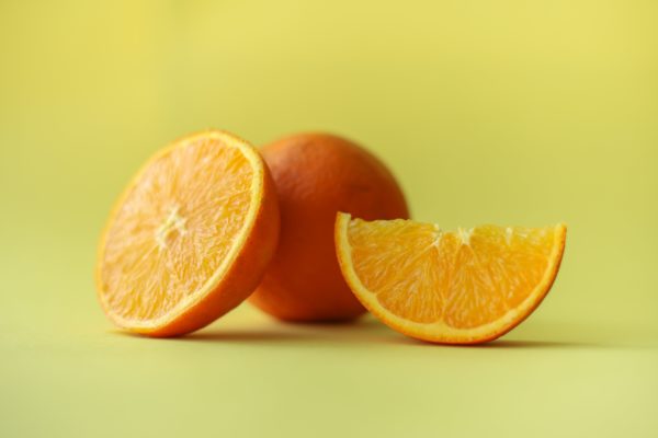 Sliced oranges on a yellow background relating to antioxidant rich foods that fight free radicals.