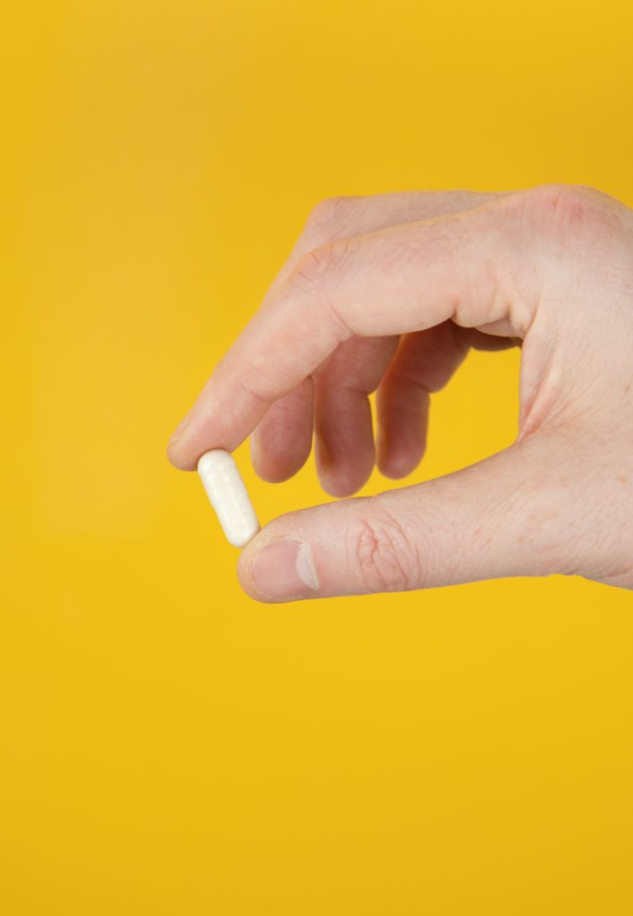 A single vitamin b3 capsule in a man's hand.